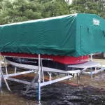 red boat lifted out of water and covered by green canopy