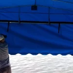 man installing blue canopy on boat lift