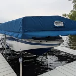 white boat with blue canopy covering it on boat lift