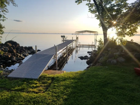 Custom Portable dock on lake, grassy lawn and tree with the sun shining through the branches