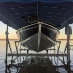 front view of boat lifted out of the water underneath a blue canopy