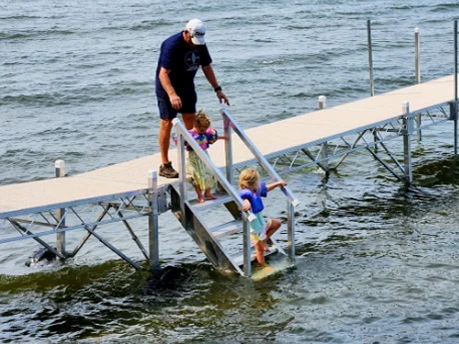 father and children on dock help them out of the water