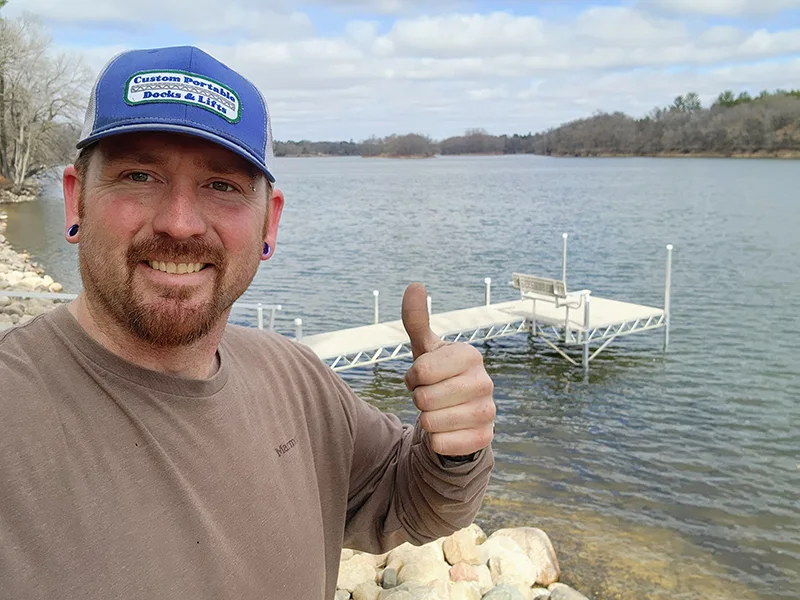 Man wearing blue hat giving a thumbs up with custom dock in the back ground